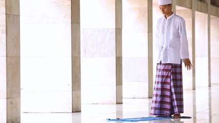 Wall Mural - Young muslim person praying on the mat in Istiqlal Mosque