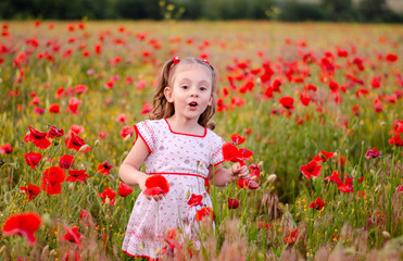 a little girl with blond hair in a bright dress with an ornament stands among a poppy field