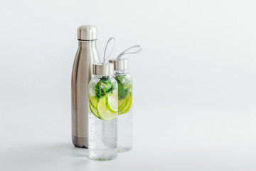  Fresh lime and mint infused water, cocktail, detox drink, lemonade in reusable bottles. Summer drinks. Health care concept.