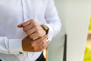 Wall Mural - Man in the white shirt wearing the watch on the balcony of your room in the background of the garden. The groom is going to the wedding. The entrepreneur is preparing for the working day.