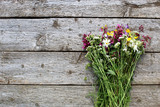 Fototapeta Lawenda - Bouquet of wildflowers lies on the old wooden background