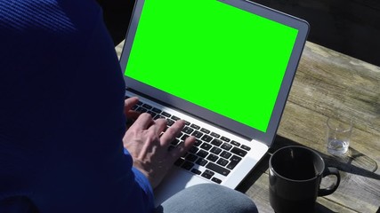Close up creative man typing on laptop keyboard with green screen chroma.