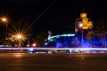 Poster - meteki church at night with street and driving cars in front