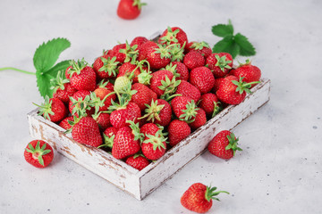 Strawberries in a box on the white concrete background