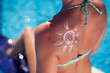 © Aleksej - Woman with sun crem on her back in shape of sun. People, summer, vacation and healthcare concept