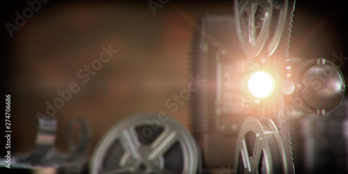 Foto  Movie projector with light beam and film reels on dark background
