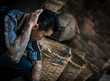 young hip tattooed asian man sitting in rural Hong Kong villiage