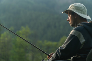 Wall Mural - young man in a wheelchair fishing at the beautiful lake in sunset, dawn