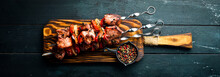 Shish Kebab BBQ Meat With Onions And Tomatoes. On A Black Background. Top View. Free Space For Your Text. Rustic Style.