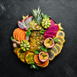 © Yaruniv-Studio - A plate of sliced tropical fruit. Top view. Free space for text.