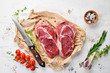Raw juicy ribeye steaks with spices on a white wooden table. Top view. Free space for your text.