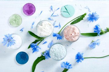 Wall Mural - moisturizers, bath salts and powder compacts with blue chicory flowers on white wood table