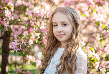 Wall Mural - candid portrait of a girl in a blooming apple orchard