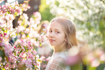 Wall Mural - candid portrait of a girl in a blooming apple orchard