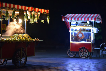 Street food carts in night. Text on signboards in translation from Turkish language on English is Roasted chestnuts and corn.