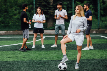 Wall Mural - What about new palyer. Young, attractive blonde  woman  holding a soccer ball, competitive attitude, excited to play a game..