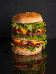 A large rustic Hamburger on a dark wooden table. Fast food. Copy space