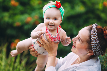 happy harmonious family outdoors. mother throws baby up, laughing and playing in the summer on the nature.