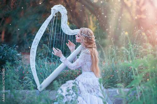 Fotografía mysterious forest nymph plays on white harp in fabulous place, girl with long blond hair and elegant lace vintage dress calling for bright sun rays, lady with silver jewelry and musical instrument