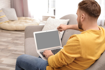 Poster - Young man using video chat on laptop in living room. Space for design