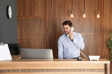 Receptionist talking on phone at desk in lobby