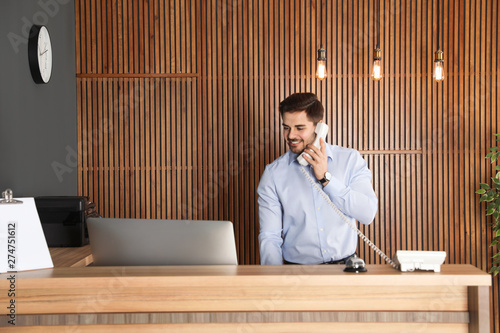 Fotografía Receptionist talking on phone at desk in lobby