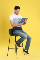 Sticker - Handsome man reading book on color background