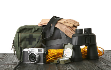 Set with different camping equipment on wooden table against white background