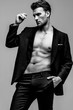 Portrait of a shirtless young and handsome model in a black suit. Studio shot. Copy space