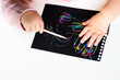© Inna - Close up of Happy girl hands drawing on magic scratch colorful painting paper with drawing stick.