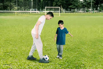 Wall Mural - Father playing football with his son in the field