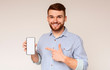 © Prostock-studio - Smiling millennial man holding latest slim cellphone