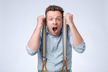 Wall Mural - Shocked face of young european man in blue shirt and suspenders