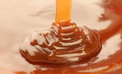 Wall Mural - Pouring delicious caramel sauce as background, closeup