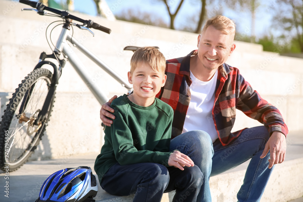 Father and his son with bicycle outdoors