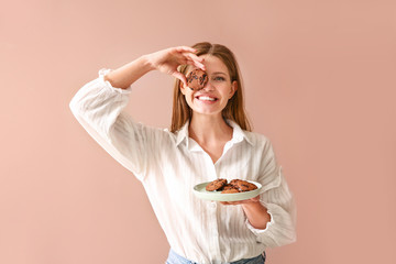 Happy woman with tasty cookies on color background