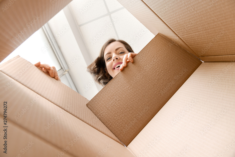 Young woman opening parcel at home, view from inside of box - obrazy, fototapety, plakaty 