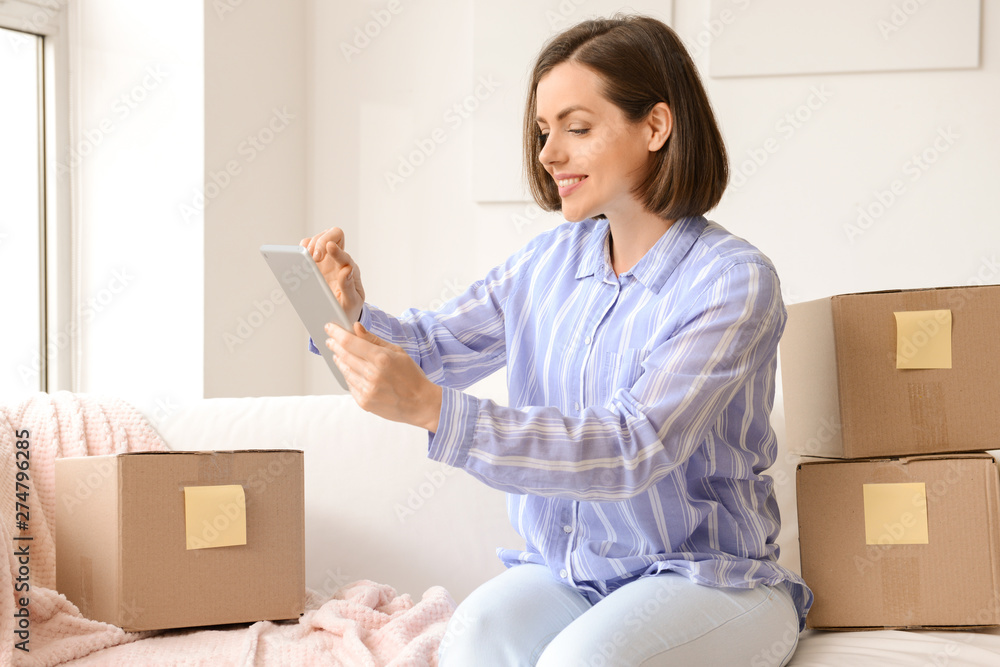 Young woman with parcels and tablet computer at home