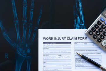 Wall Mural - work injury claim form with pen and calculator on top of an X-ray film medical and insurance concept