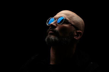 Bald man with grey beard in sunglass on dark background