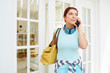 © DragonImages - Pretty young woman standing at house entrance and talking on phone