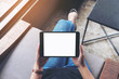 © Farknot Architect - Top view mockup image of a woman holding black tablet pc with blank white screen while sitting in cafe
