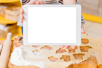 Cooking video tutorial. Closeup of white mockup tablet screen. Woman holding device over rolled dough on the table.