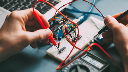 Engeneer workplace. Technician testing microcontroller. Top view of electronic components and wires.