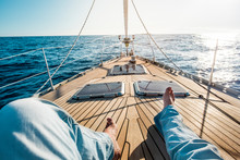 Happiness And Relax Concept For Traveler People - Man Legs Point Of View On A Wooden Sail Boat With Sun And Blue Ocean Around - Luxury And Holiday Vacation Outdoor Leisure Activity