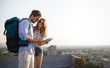 © NDABCREATIVITY - Happy couple on vacation sightseeing city with map
