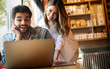 © NDABCREATIVITY - Couple have fun while looking on laptop at cafe