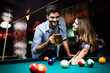 © NDABCREATIVITY - Happy young man playing snooker with his girlfriend. Happy loving couple.