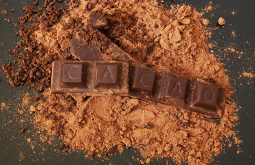 Chocolate bars with word CACAO on cacao powder close up