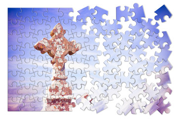 Patiently building of faith - Celtic carved stone cross against a sky background - concept image in jigsaw puzzle shape